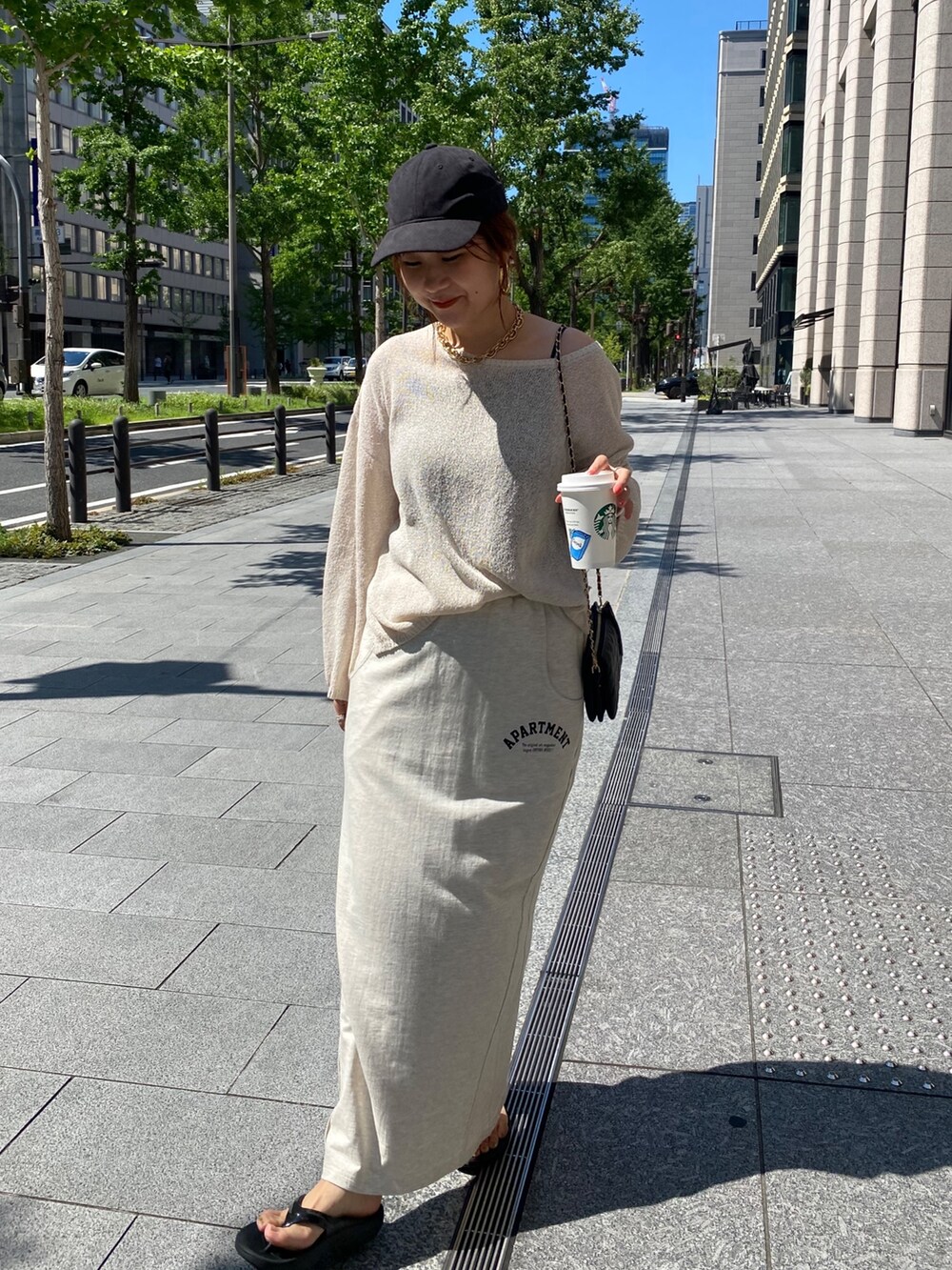 ベージュ系のニット/セーター、ベージュ系のスカート、ブラック系のショルダーバッグを着用したレディースの夏コーディネートの3枚目の写真