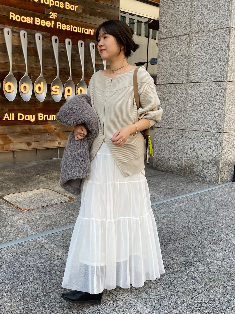 ベージュ系のニット/セーター、ホワイト系のスカート、グレー系のその他アウターを着用したレディースの冬コーディネートの5枚目の写真