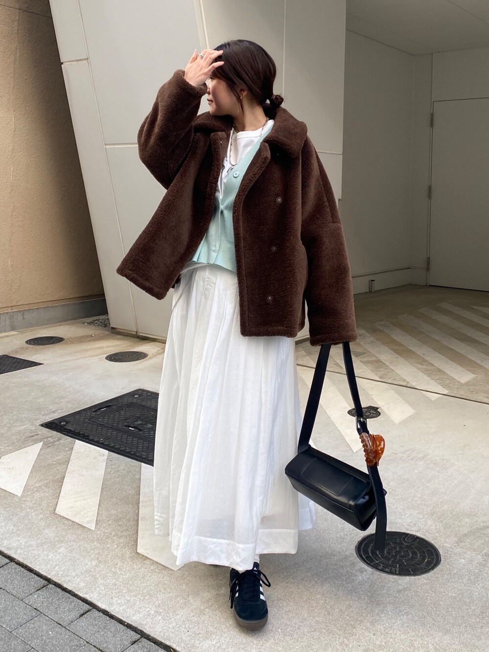 グリーン系のカーディガン/ボレロ、ホワイト系のスカートを着用したレディースの冬コーディネートの9枚目の写真