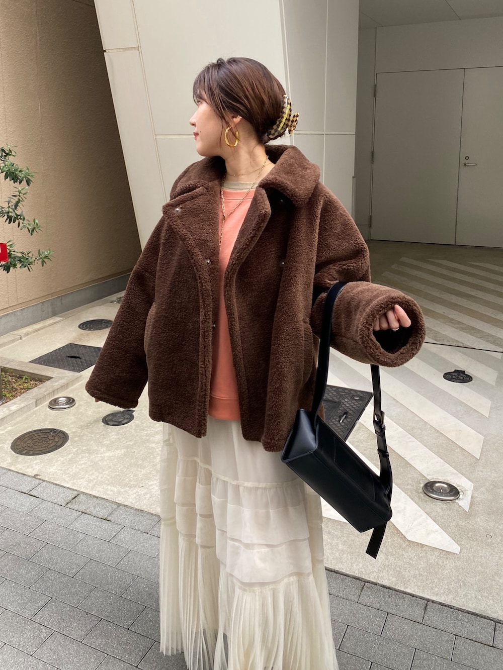 ブラウン系のその他アウター、オレンジ系のスウェット、ホワイト系のスカートを着用したレディースの冬コーディネートの9枚目の写真