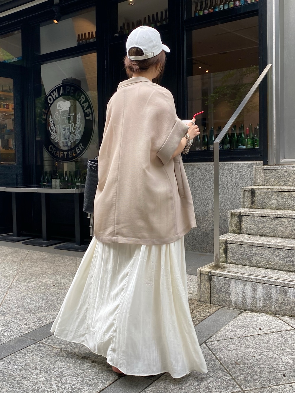 ホワイト系のワンピース、ベージュ系のテーラードジャケット、ホワイト系のキャップを着用したレディースの夏コーディネートの9枚目の写真