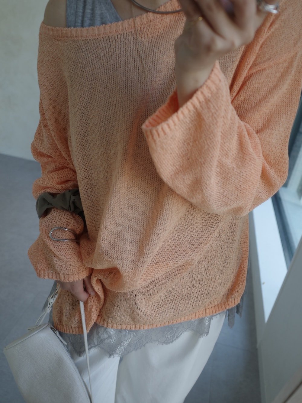 オレンジ系のニット/セーター、グレー系のTシャツ/カットソー、ホワイト系のその他パンツを着用したレディースの春コーディネートの5枚目の写真