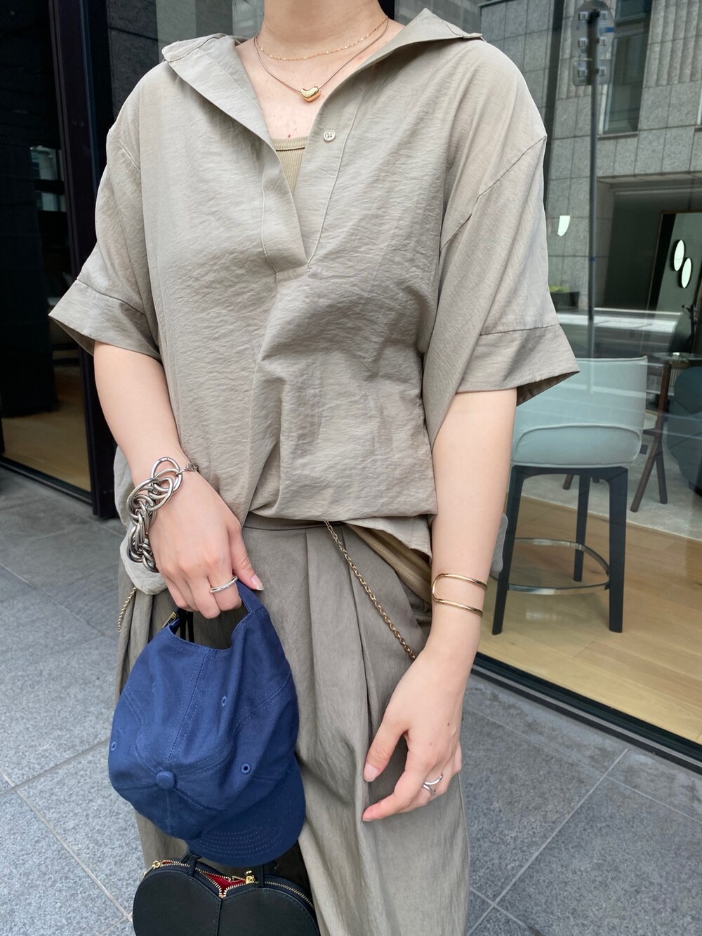 ベージュ系のシャツ/ブラウス、ブラック系のショルダーバッグ、ベージュ系のTシャツ/カットソーを着用したレディースの夏コーディネートの4枚目の写真