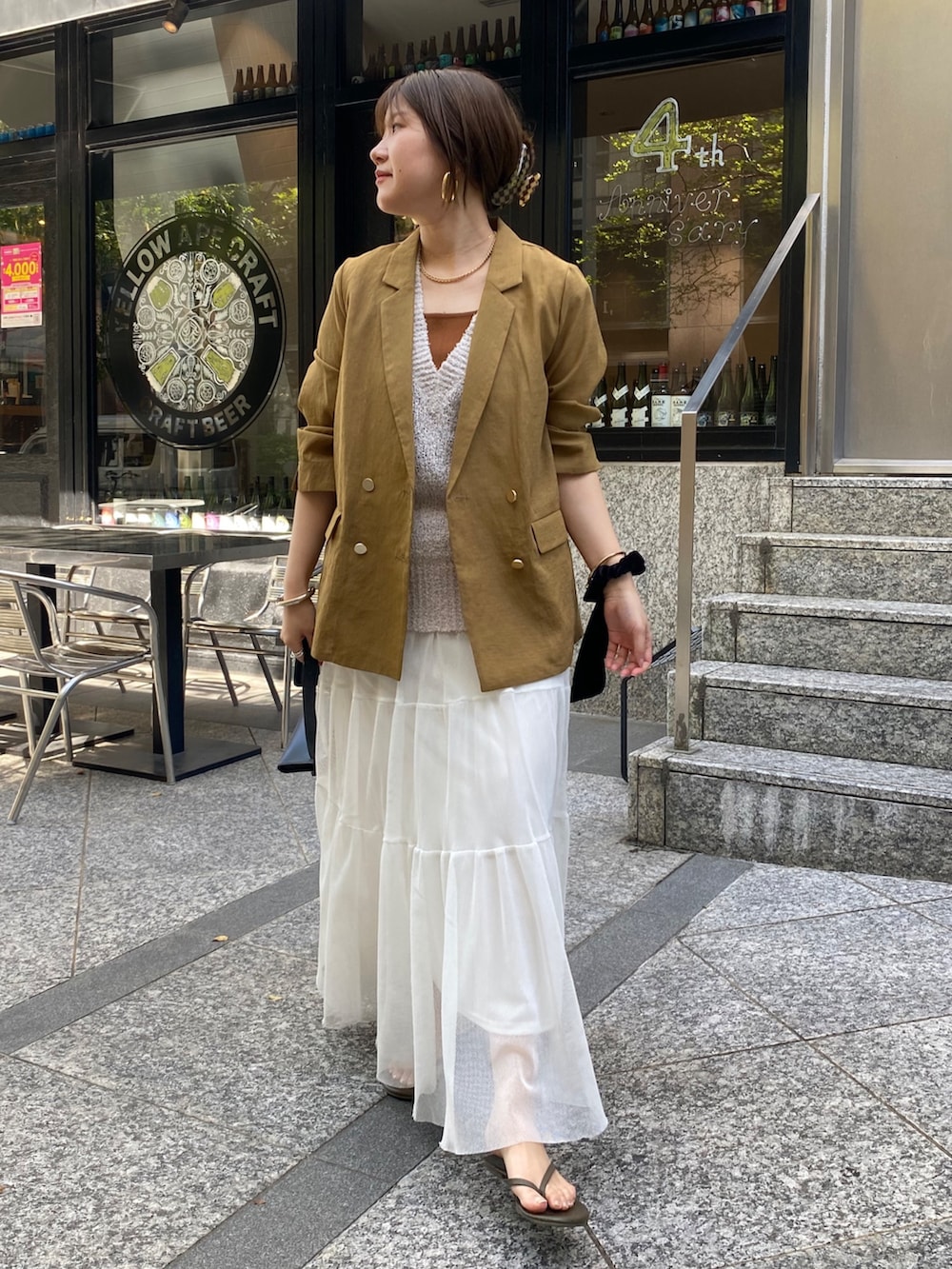 イエロー系のテーラードジャケット、ベージュ系のニット/セーター、ブラウン系のタンクトップを着用したレディースの夏コーディネートの3枚目の写真