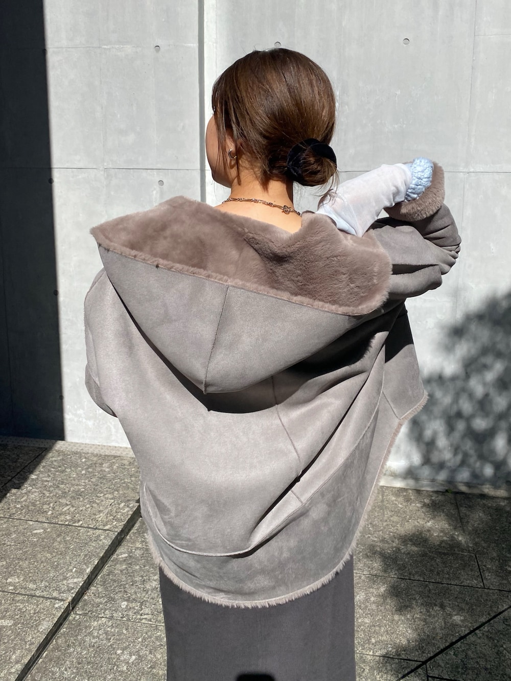 ブルー系のニット/セーター、ブルー系のTシャツ/カットソー、グレー系のムートンコートを着用したレディースの冬コーディネートの5枚目の写真