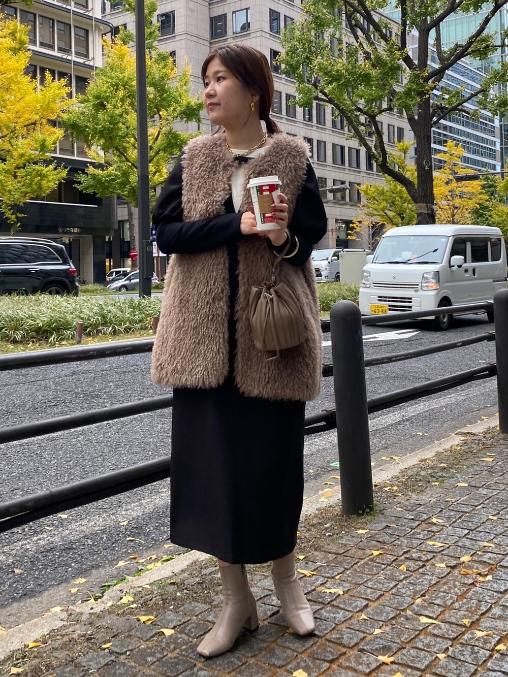 ベージュ系のベスト、ブラック系のワンピースを着用したレディースの秋コーディネートの4枚目の写真