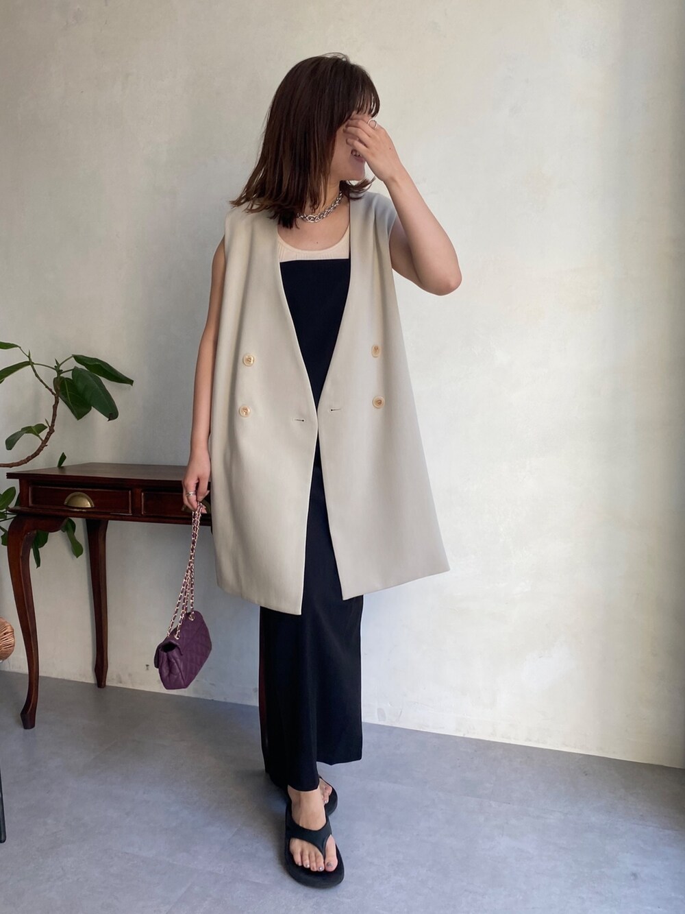 ベージュ系のベスト、ブラック系のワンピース、ブラック系のサンダルを着用したレディースの夏コーディネートの4枚目の写真