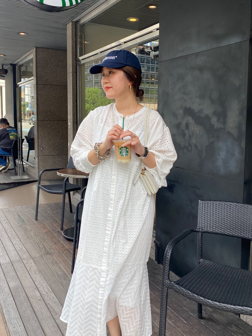 ホワイト系のワンピース、ホワイト系のショルダーバッグ、ゴールド系のブレスレットを着用したレディースの夏コーディネートの2枚目の写真