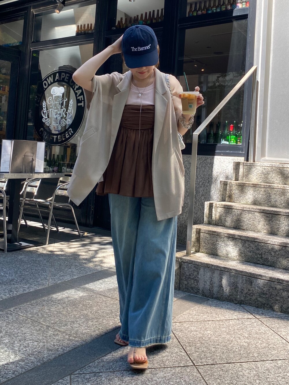 ベージュ系のテーラードジャケット、ブラウン系のキャミソール、ブルー系のデニムパンツを着用したレディースの夏コーディネートの3枚目の写真