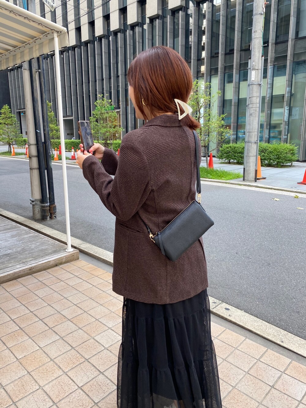 ブラウン系のテーラードジャケット、ブラック系のスカート、ブラック系のショルダーバッグを着用したレディースの秋コーディネートの6枚目の写真