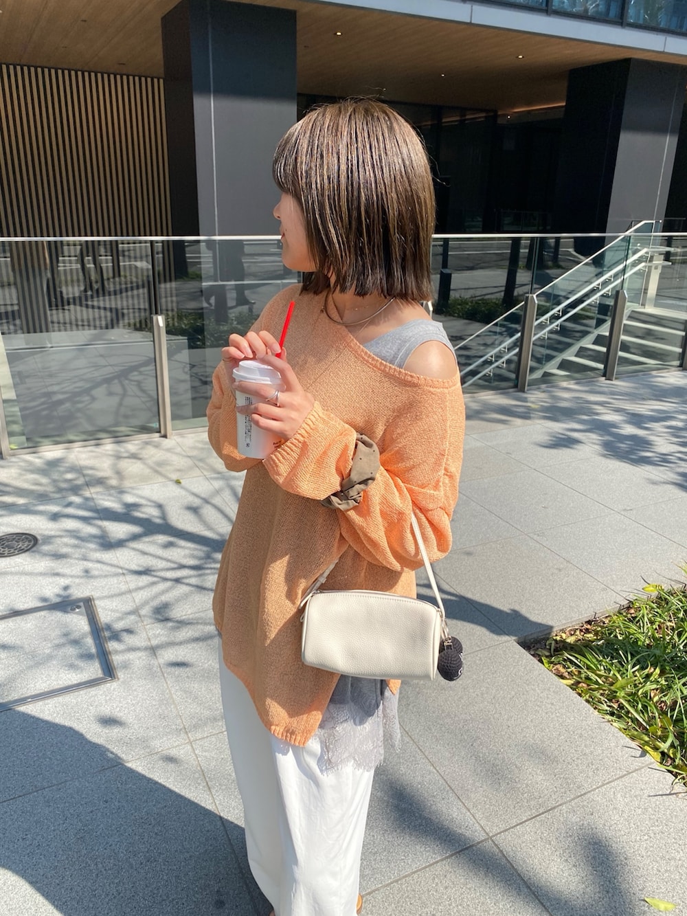 オレンジ系のニット/セーター、グレー系のTシャツ/カットソー、ホワイト系のその他パンツを着用したレディースの春コーディネートの2枚目の写真