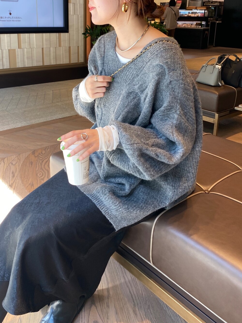 グレー系のニット/セーター、ブラック系のスカートを着用したレディースの秋コーディネートの7枚目の写真