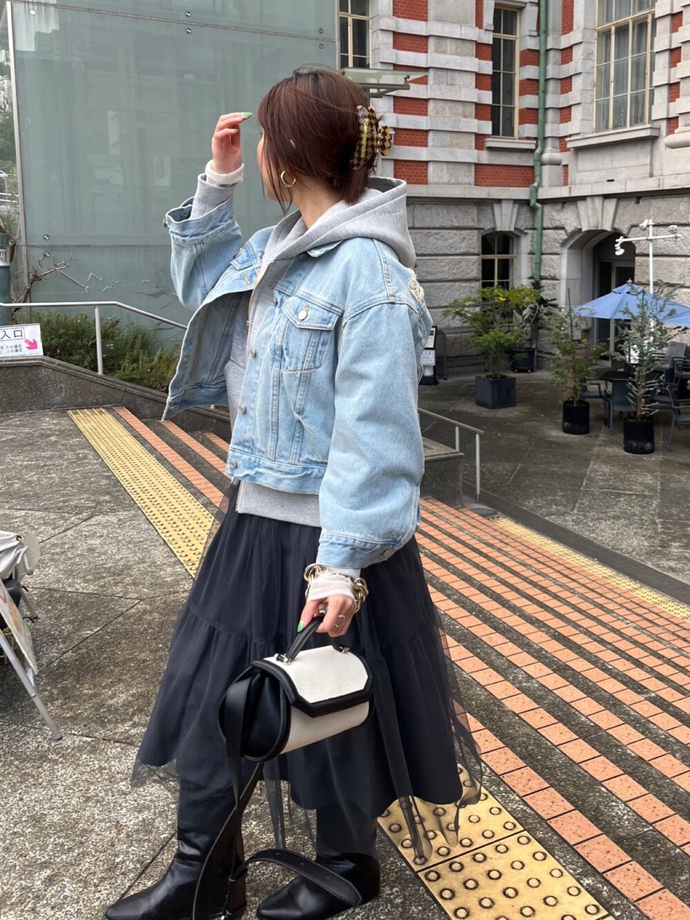 ブルー系のデニムジャケット、グレー系のワンピース、グレー系のパーカーを着用したレディースの春コーディネートの5枚目の写真