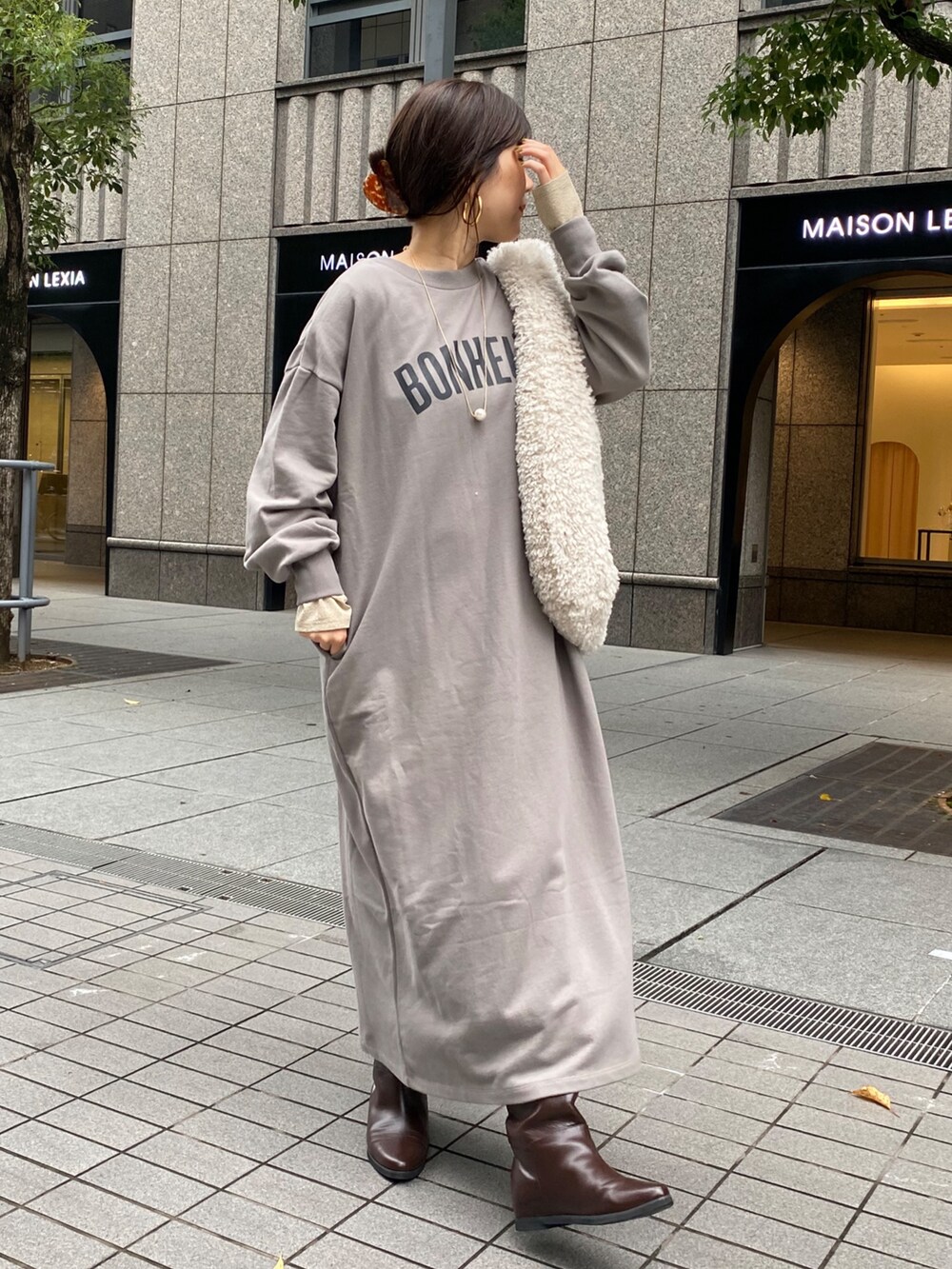 グレー系のワンピース、ブラウン系のブーツ、ゴールド系のTシャツ/カットソーを着用したレディースの秋コーディネートの4枚目の写真