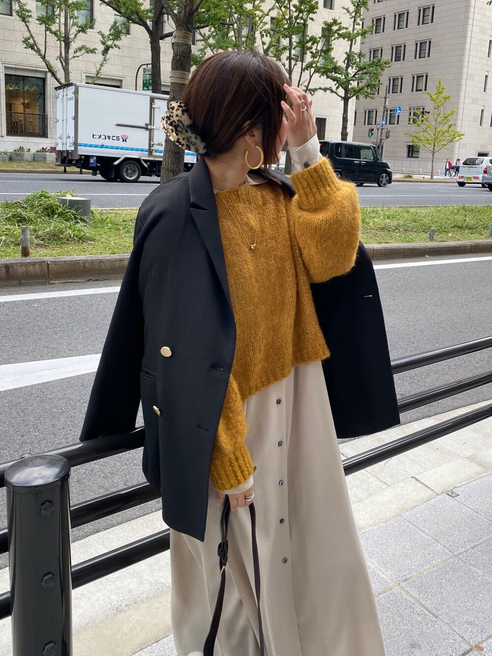 イエロー系のニット/セーター、ベージュ系のワンピース、ブラック系のテーラードジャケットを着用したレディースの冬コーディネートの7枚目の写真