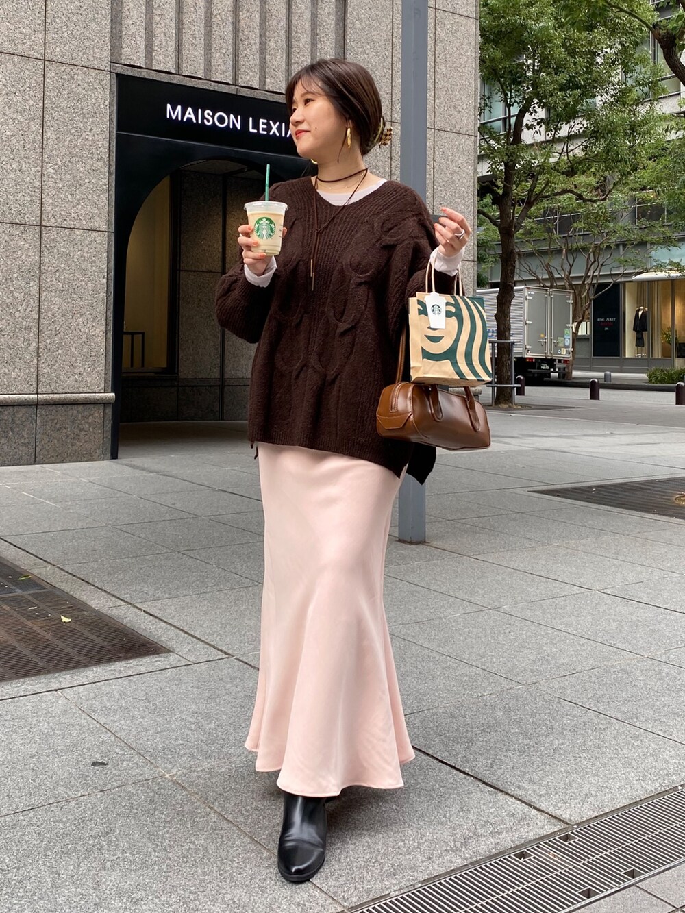 ブラウン系のニット/セーター、ピンク系のスカート、ブラック系のブーツを着用したレディースの冬コーディネートの8枚目の写真