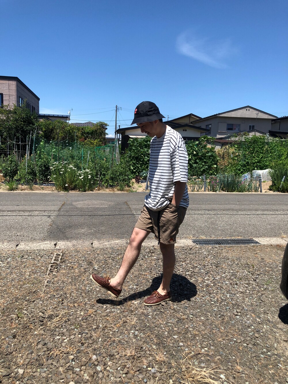 ホワイト系のTシャツ/カットソー、ベージュ系のその他パンツ、ブラウン系のモカシン/デッキシューズを着用したメンズの夏コーディネートの2枚目の写真