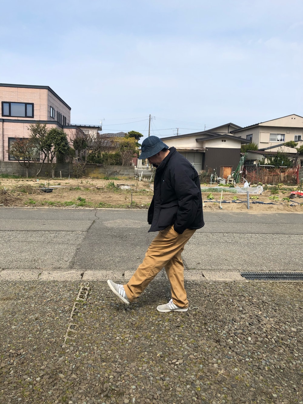 ブラック系のダウンジャケット/コート、ベージュ系のその他パンツを着用したメンズの春コーディネートの2枚目の写真