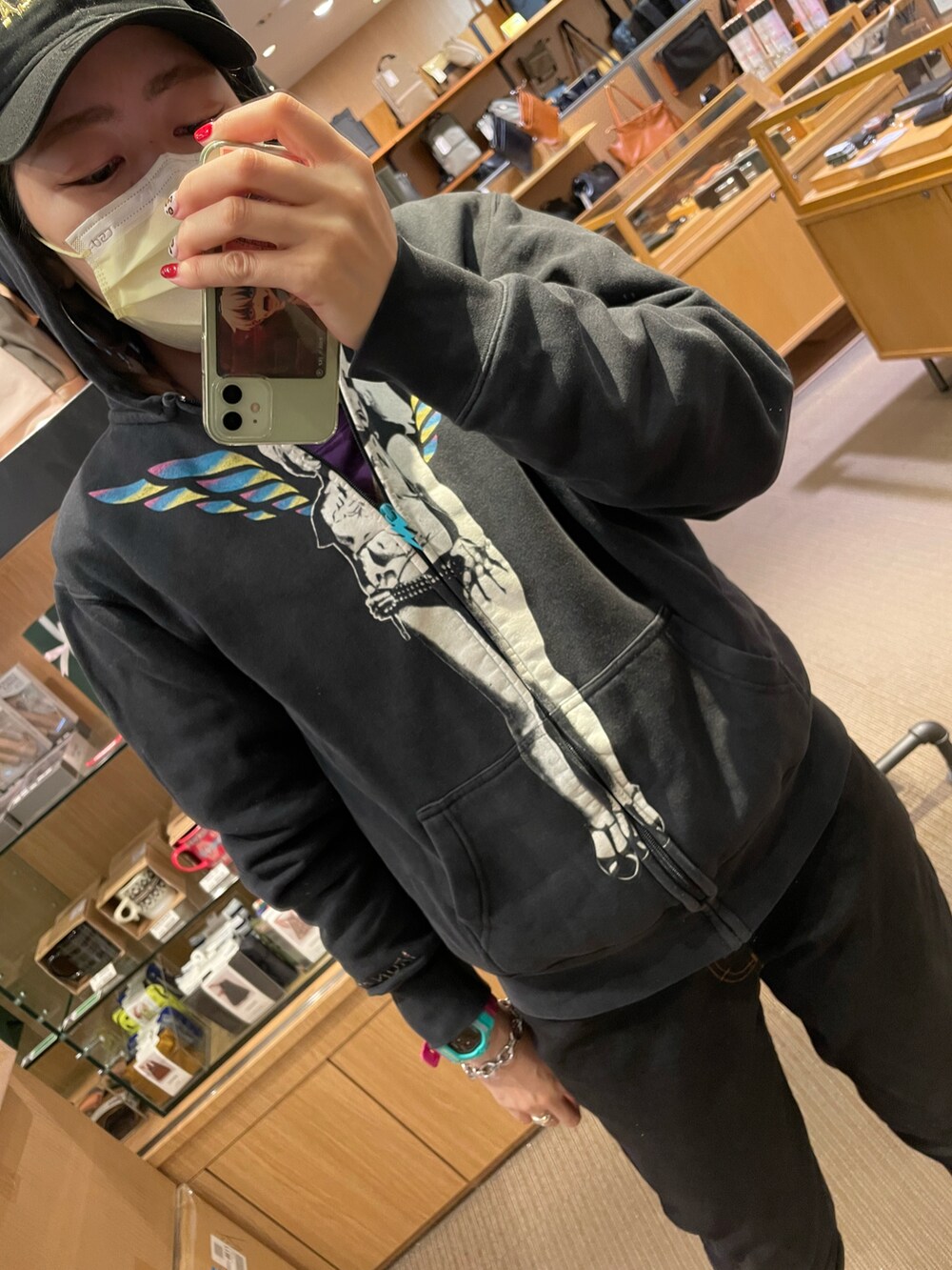 ブラック系のパーカー、ブラック系のデニムパンツ、パープル系のスニーカーを着用したレディースの春コーディネートの2枚目の写真