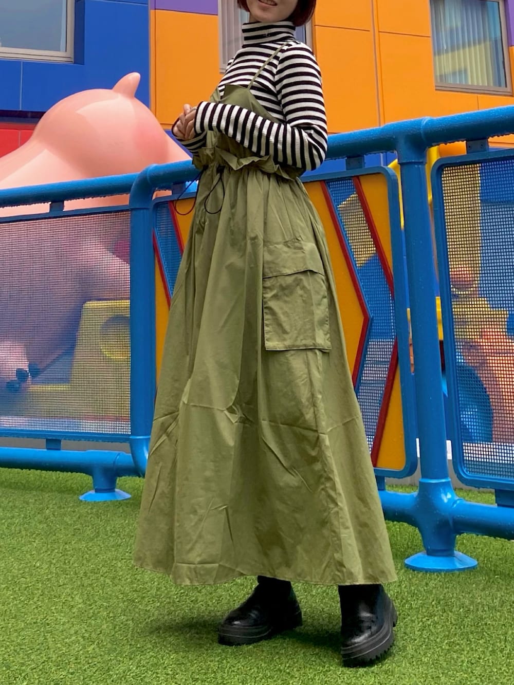 ブラック系のブーツ、グリーン系のワンピース、ブラック系のTシャツ/カットソーを着用したレディースの冬コーディネートの2枚目の写真