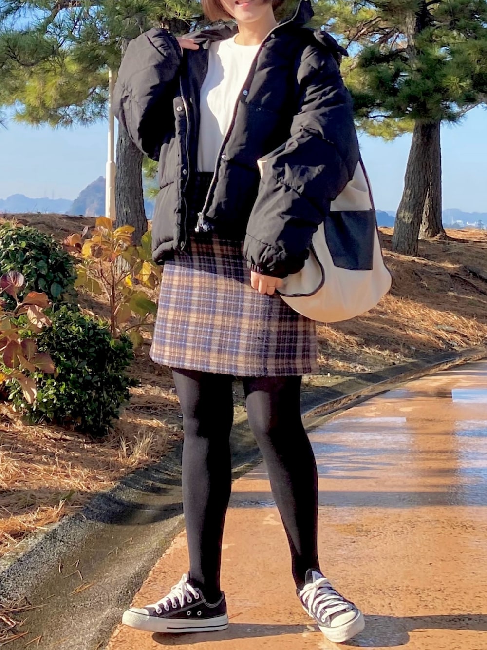 ブラック系のスニーカー、ホワイト系のトートバッグ、ブラック系のダウンジャケット/コートを着用したレディースの冬コーディネートの2枚目の写真