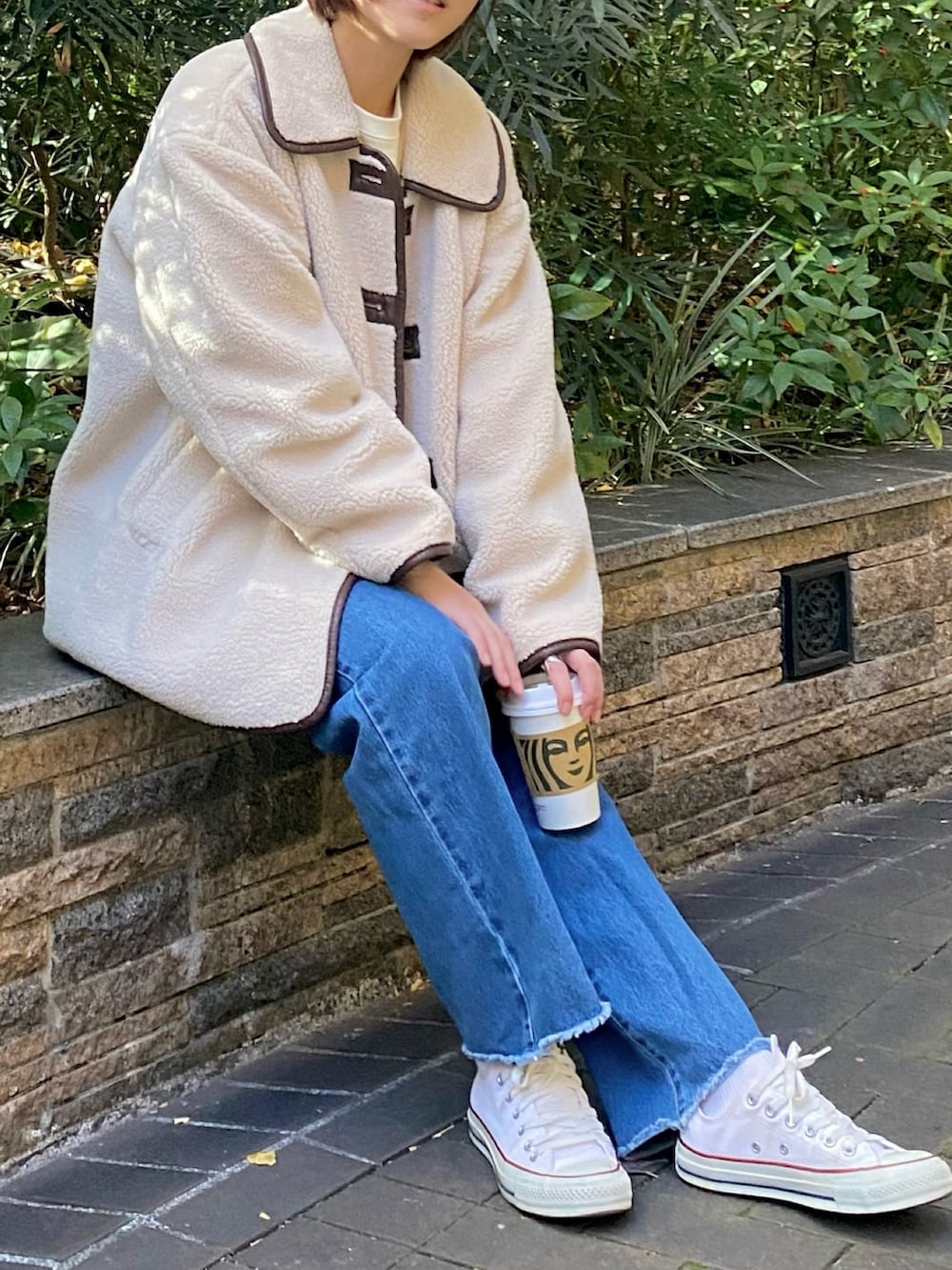ベージュ系のブルゾン、ホワイト系のスウェット、ブルー系のデニムパンツを着用したレディースの冬コーディネートの2枚目の写真