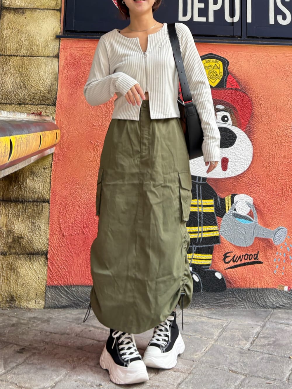 ブラック系のスニーカー、グリーン系のスカート、シルバー系のリングを着用したレディースの春コーディネートの2枚目の写真