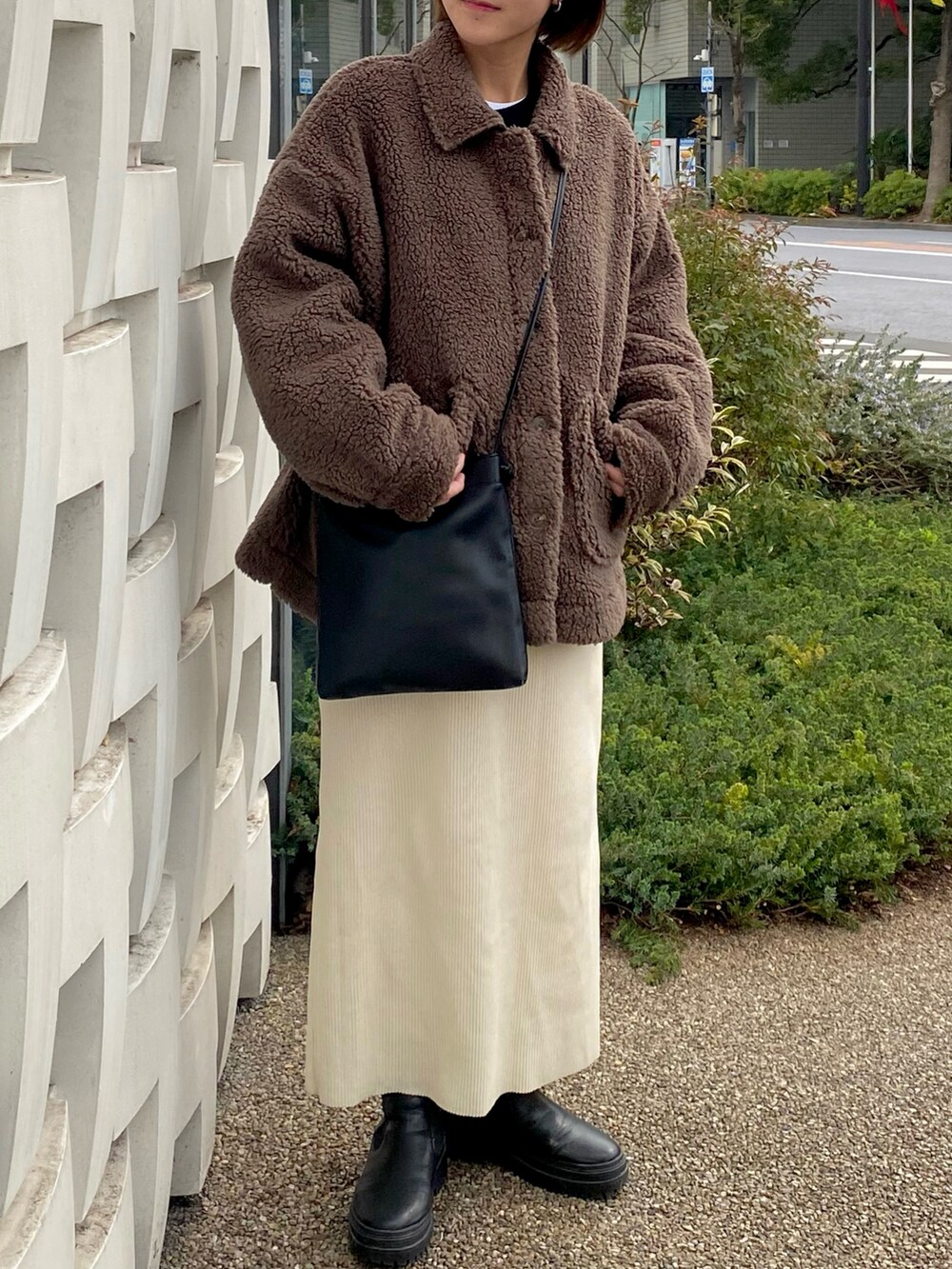 ブラウン系のブルゾン、ホワイト系のスカート、ブラック系のブーツを着用したレディースの春コーディネートの2枚目の写真