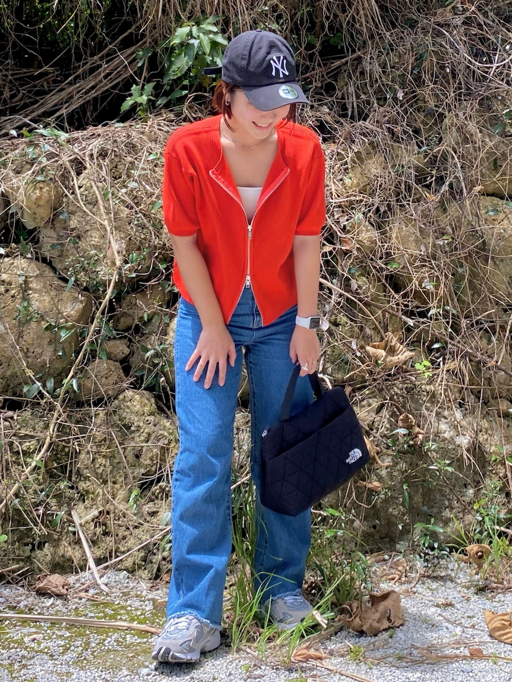 ブラック系のトートバッグ、レッド系のカーディガン/ボレロ、ブルー系のデニムパンツを着用したレディースの夏コーディネートの2枚目の写真