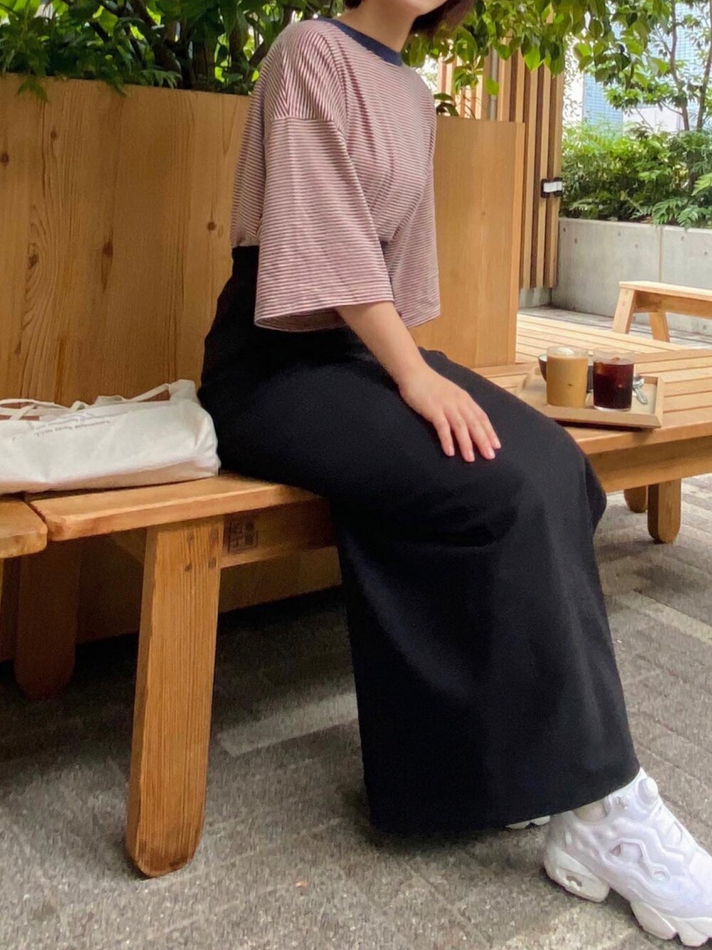 ブラック系のスカート、ホワイト系のトートバッグ、ホワイト系のスニーカーを着用したレディースの夏コーディネートの2枚目の写真