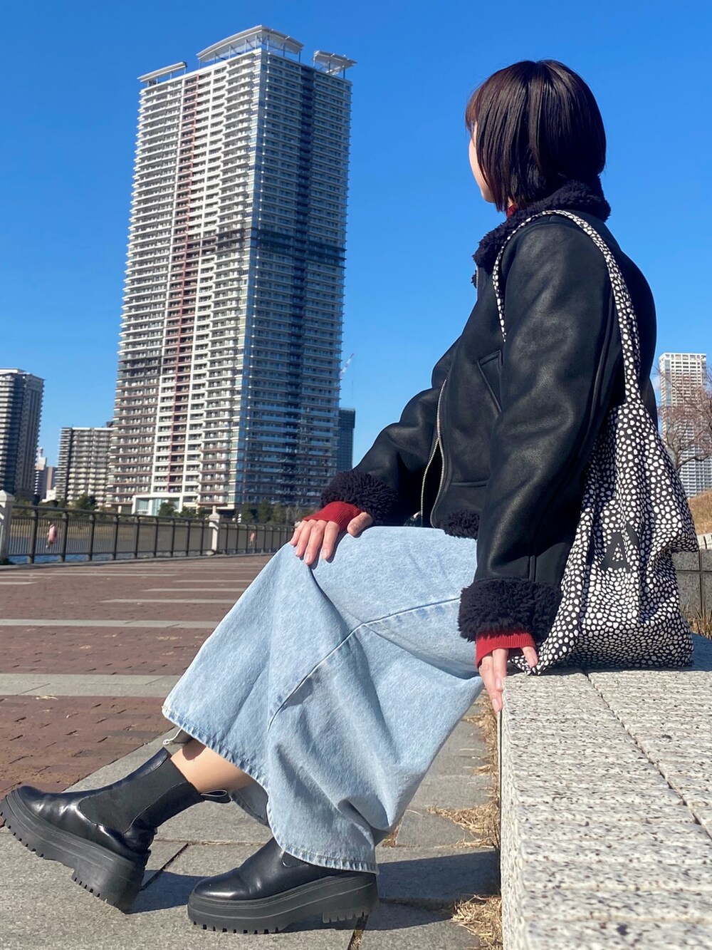 ブラック系のブーツ、ブルー系のデニムスカート、レッド系のニット/セーターを着用したレディースの冬コーディネートの2枚目の写真