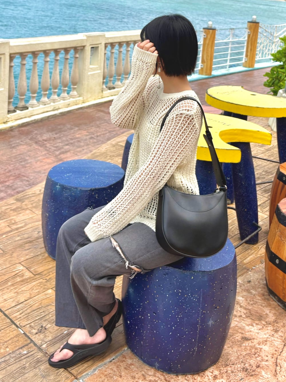 ホワイト系のニット/セーター、ブラック系のデニムパンツ、ブラック系のサンダルを着用したレディースの夏コーディネートの2枚目の写真