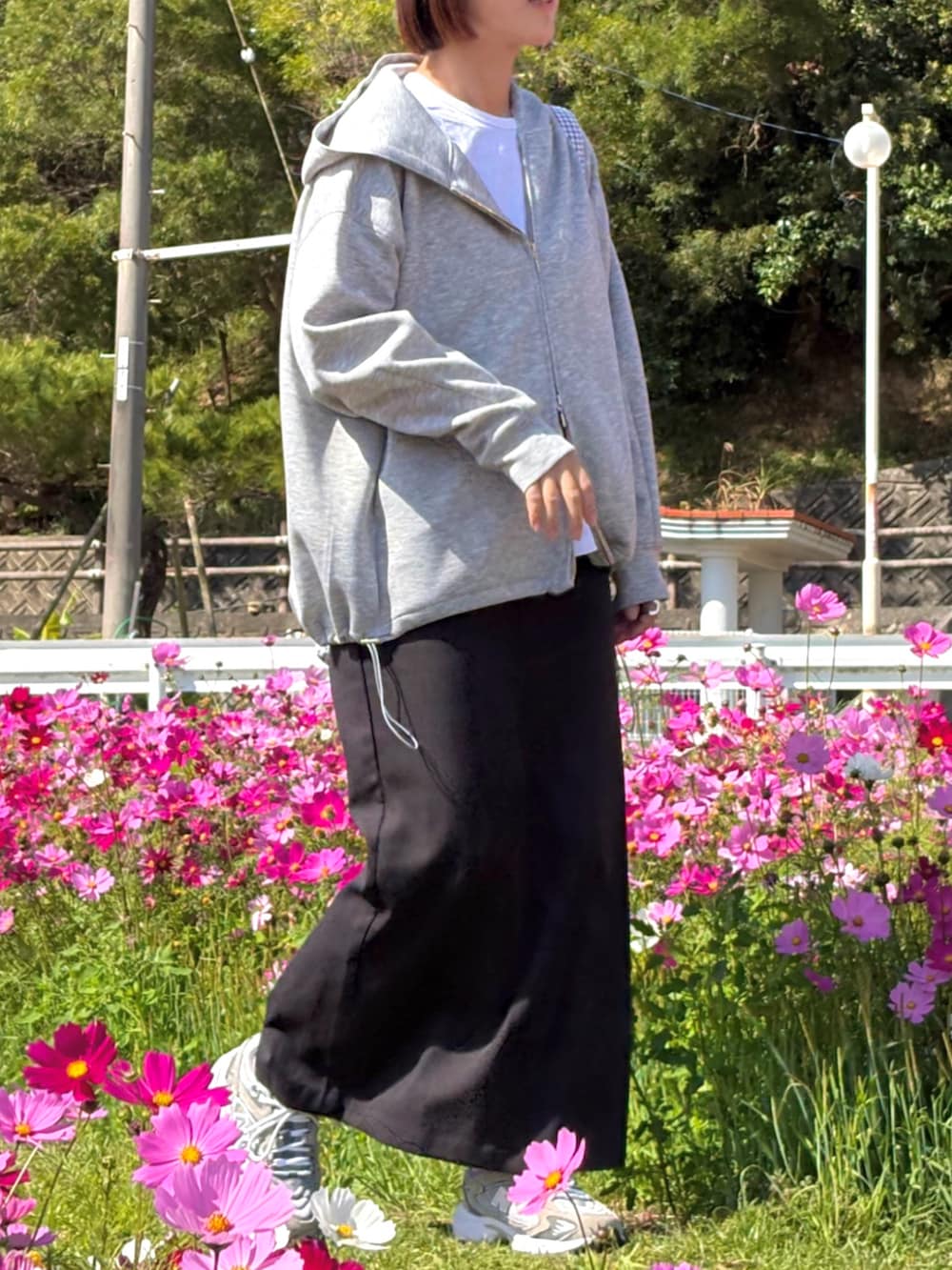 グレー系のパーカー、ブラック系のスカート、グレー系のスニーカーを着用したレディースの冬コーディネートの2枚目の写真