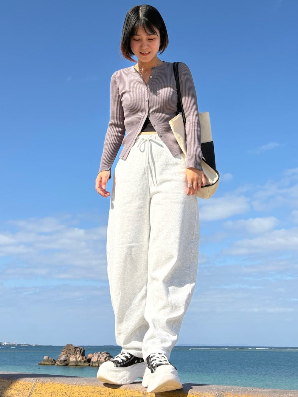 ブラック系のスニーカー、ホワイト系のトートバッグ、シルバー系のリングを着用したレディースの春コーディネートの2枚目の写真