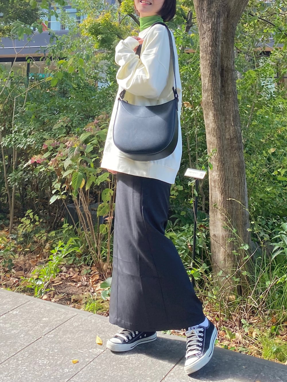 ブラック系のスニーカー、ブラック系のスカート、グリーン系のTシャツ/カットソーを着用したレディースの秋コーディネートの2枚目の写真