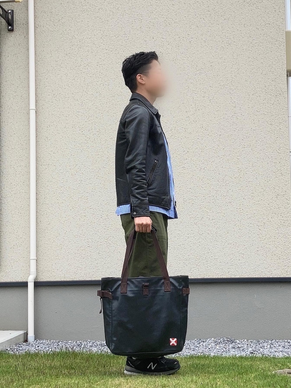 グリーン系のカーゴパンツ、ブラック系のスニーカー、ブラック系のライダースジャケットを着用したメンズの春コーディネートの2枚目の写真