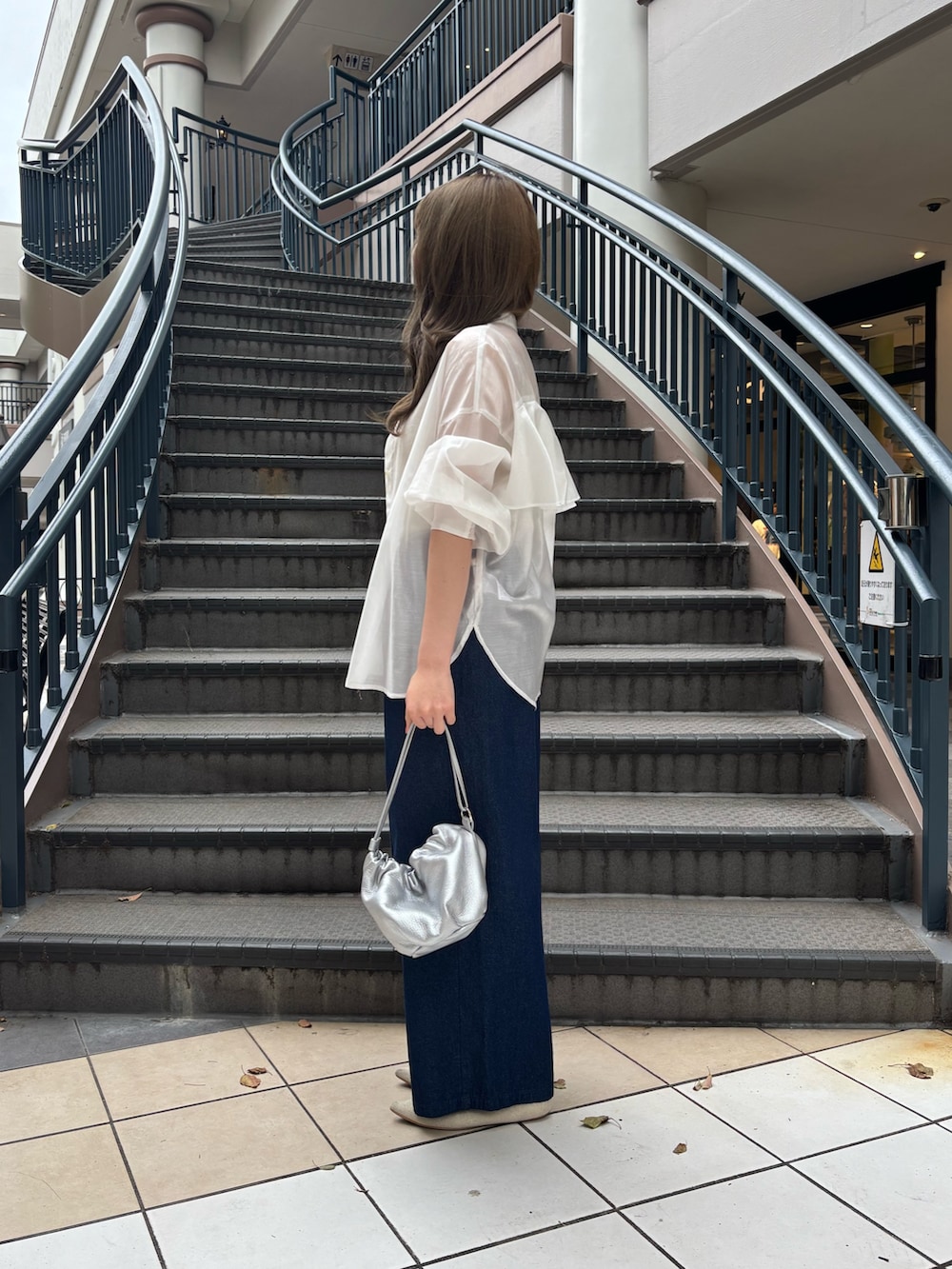 ブルー系のデニムパンツ、ホワイト系のシャツ/ブラウス、シルバー系のトートバッグを着用したレディースの夏コーディネートの2枚目の写真