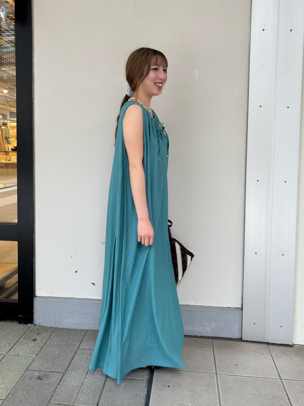 グリーン系のワンピース、ブラック系のサンダルを着用したレディースの夏コーディネートの2枚目の写真