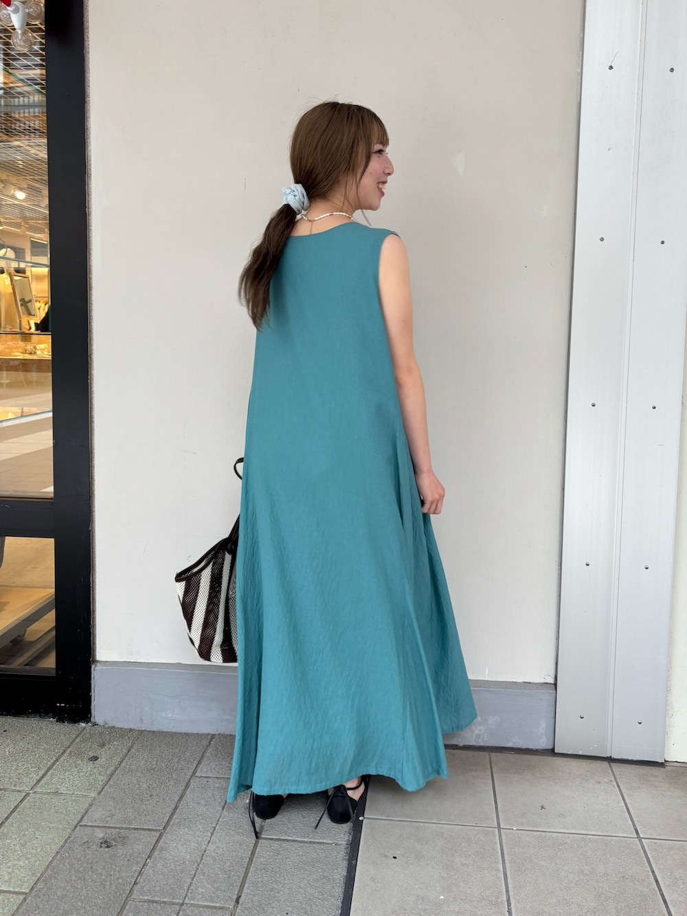 グリーン系のワンピース、ブラック系のサンダルを着用したレディースの夏コーディネートの3枚目の写真