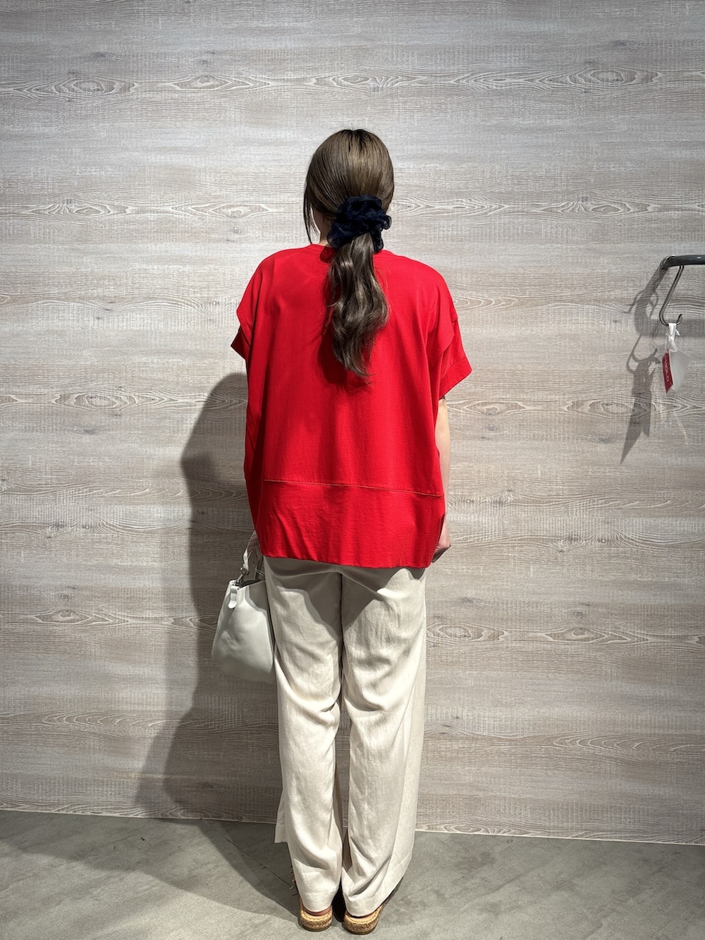 レッド系のTシャツ/カットソー、ベージュ系のその他パンツ、ホワイト系のトートバッグを着用したレディースの春コーディネートの3枚目の写真