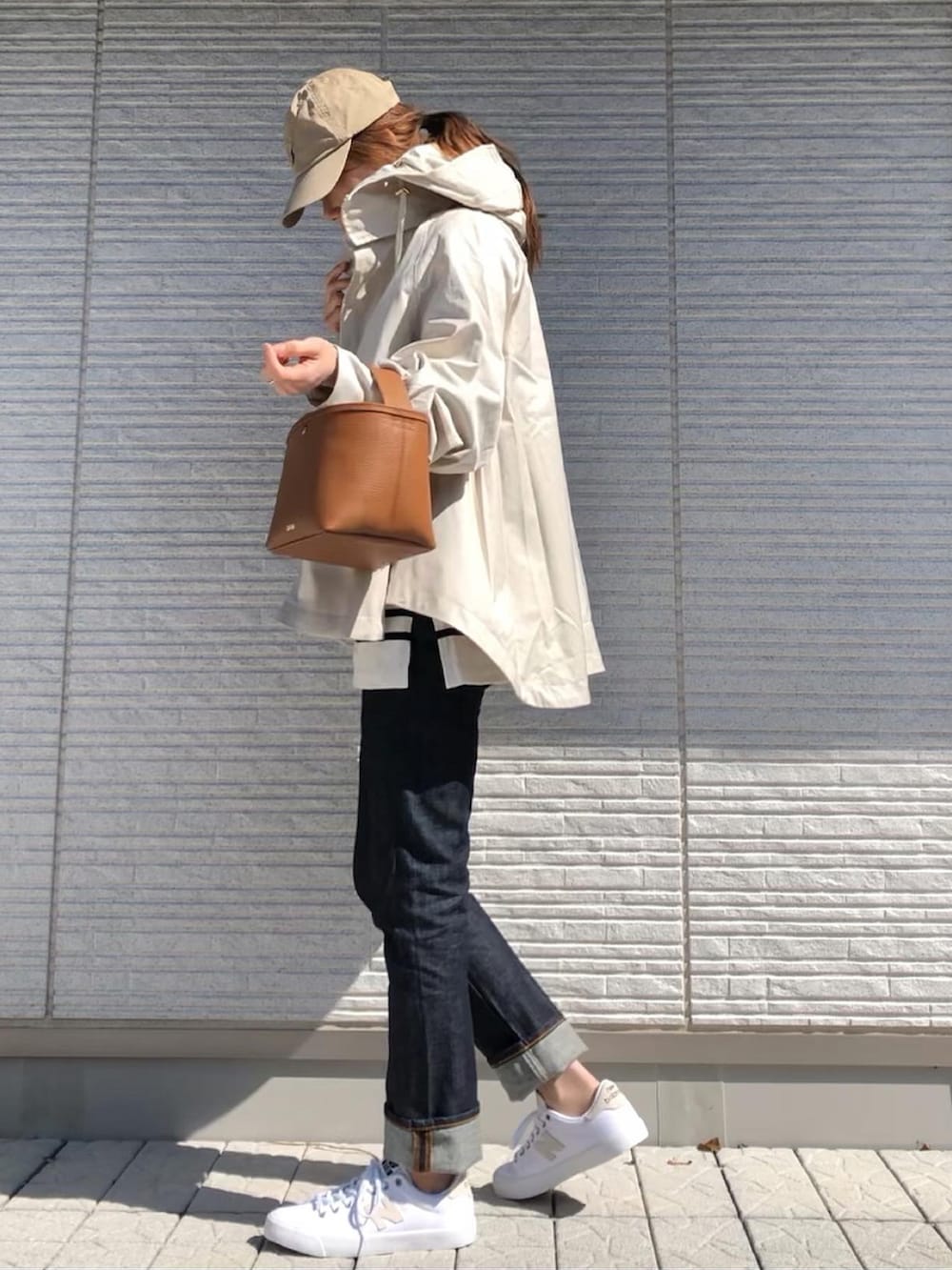 ホワイト系のスニーカー、ベージュ系のマウンテンパーカー、ベージュ系のキャップを着用したレディースの春コーディネートの2枚目の写真