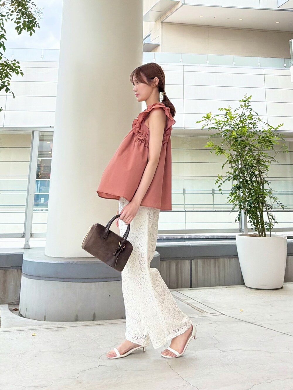 オレンジ系のシャツ/ブラウス、ホワイト系のその他パンツ、ブラウン系のボストンバッグを着用したレディースの夏コーディネートの4枚目の写真