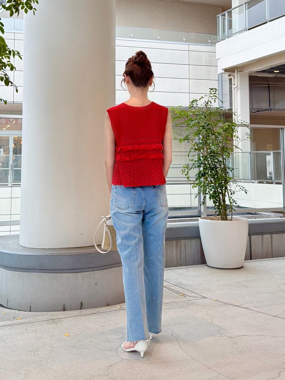 レッド系のニット/セーター、ブルー系のデニムパンツ、ホワイト系のショルダーバッグを着用したレディースの夏コーディネートの5枚目の写真