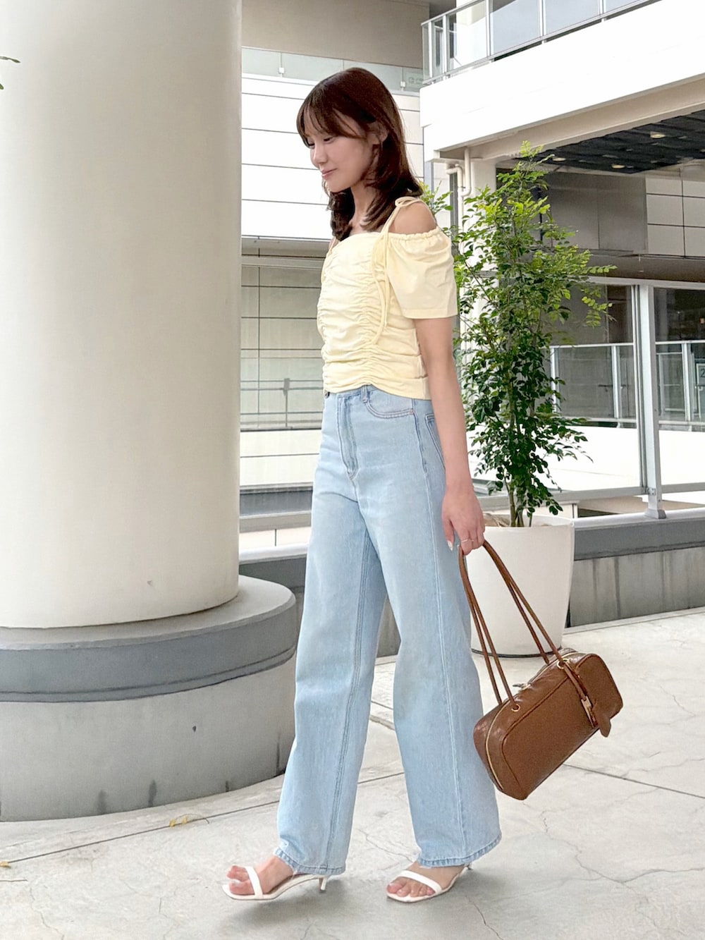 イエロー系のTシャツ/カットソー、ブルー系のデニムパンツ、ブラウン系のボストンバッグを着用したレディースの夏コーディネートの4枚目の写真