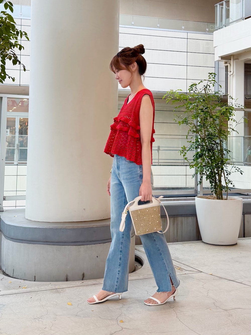 レッド系のニット/セーター、ブルー系のデニムパンツ、ホワイト系のショルダーバッグを着用したレディースの夏コーディネートの3枚目の写真