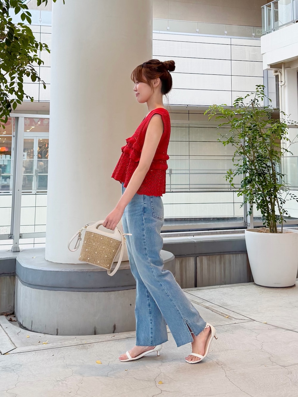 レッド系のニット/セーター、ブルー系のデニムパンツ、ホワイト系のショルダーバッグを着用したレディースの夏コーディネートの4枚目の写真