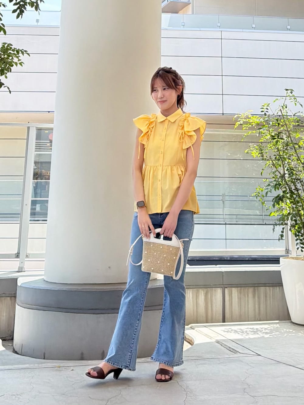 イエロー系のシャツ/ブラウス、ホワイト系のショルダーバッグ、ブルー系のデニムパンツを着用したレディースの夏コーディネートの3枚目の写真