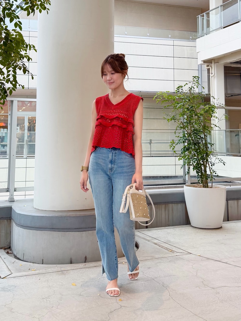 レッド系のニット/セーター、ブルー系のデニムパンツ、ホワイト系のショルダーバッグを着用したレディースの夏コーディネートの2枚目の写真