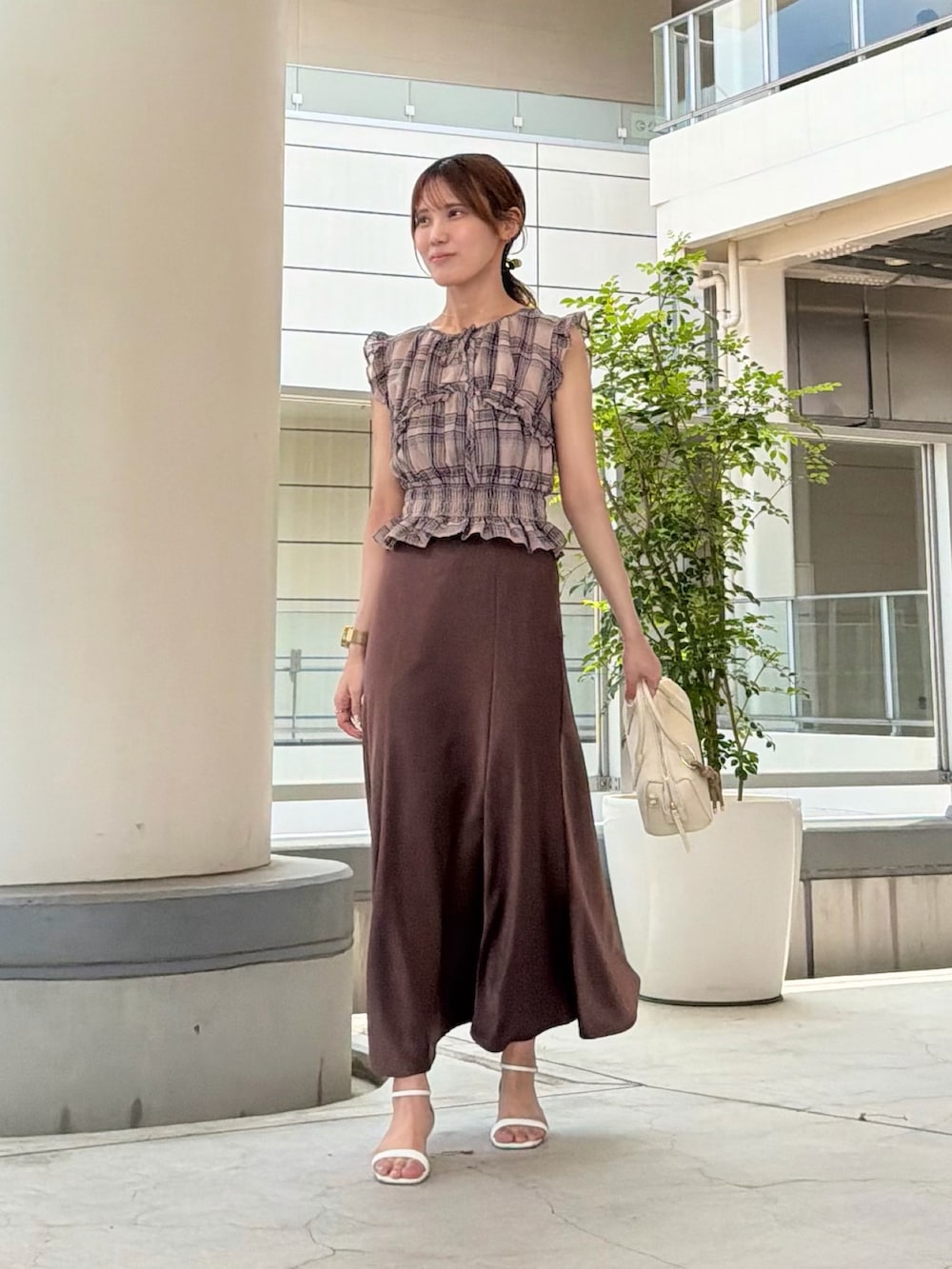 ブラウン系のスカート、ベージュ系のシャツ/ブラウス、ホワイト系のボストンバッグを着用したレディースの夏コーディネートの2枚目の写真