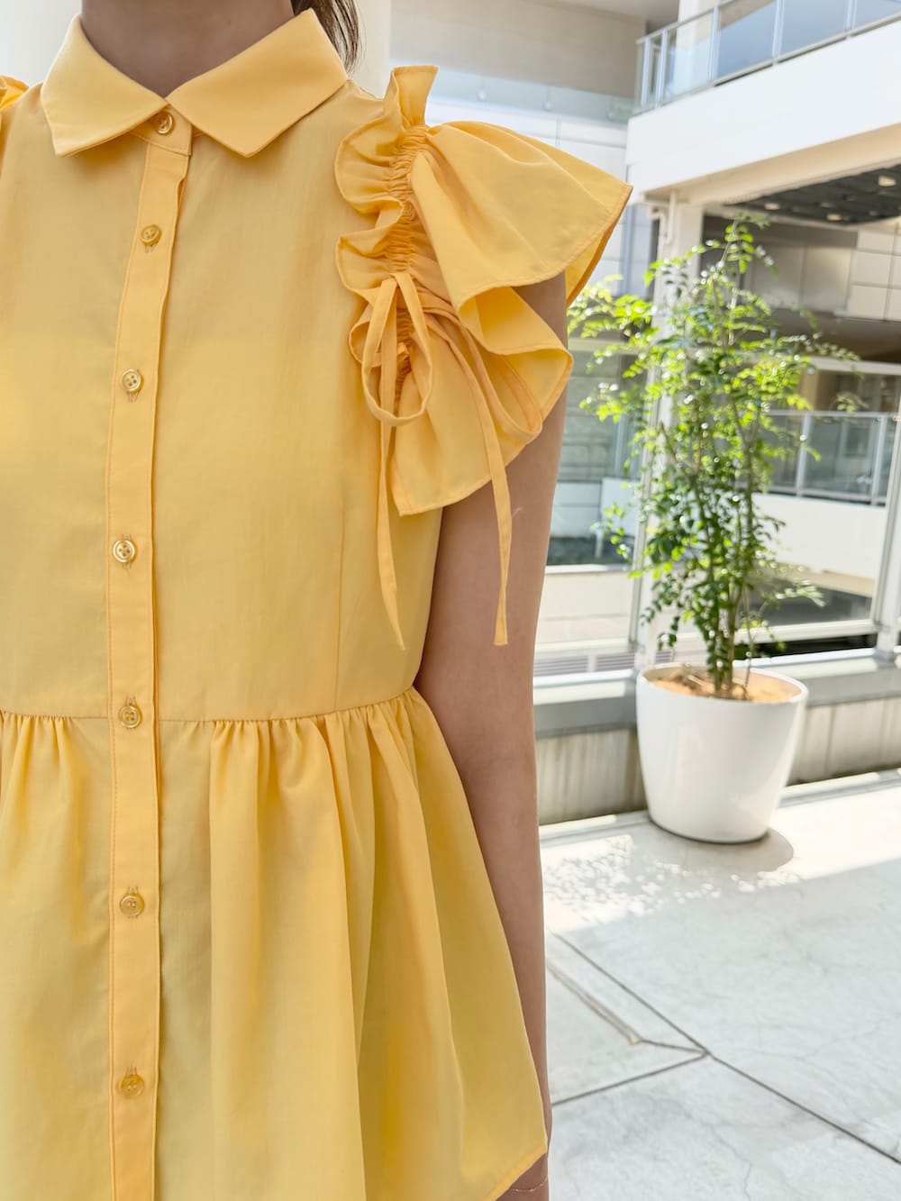 イエロー系のシャツ/ブラウス、ホワイト系のショルダーバッグ、ブルー系のデニムパンツを着用したレディースの夏コーディネートの6枚目の写真